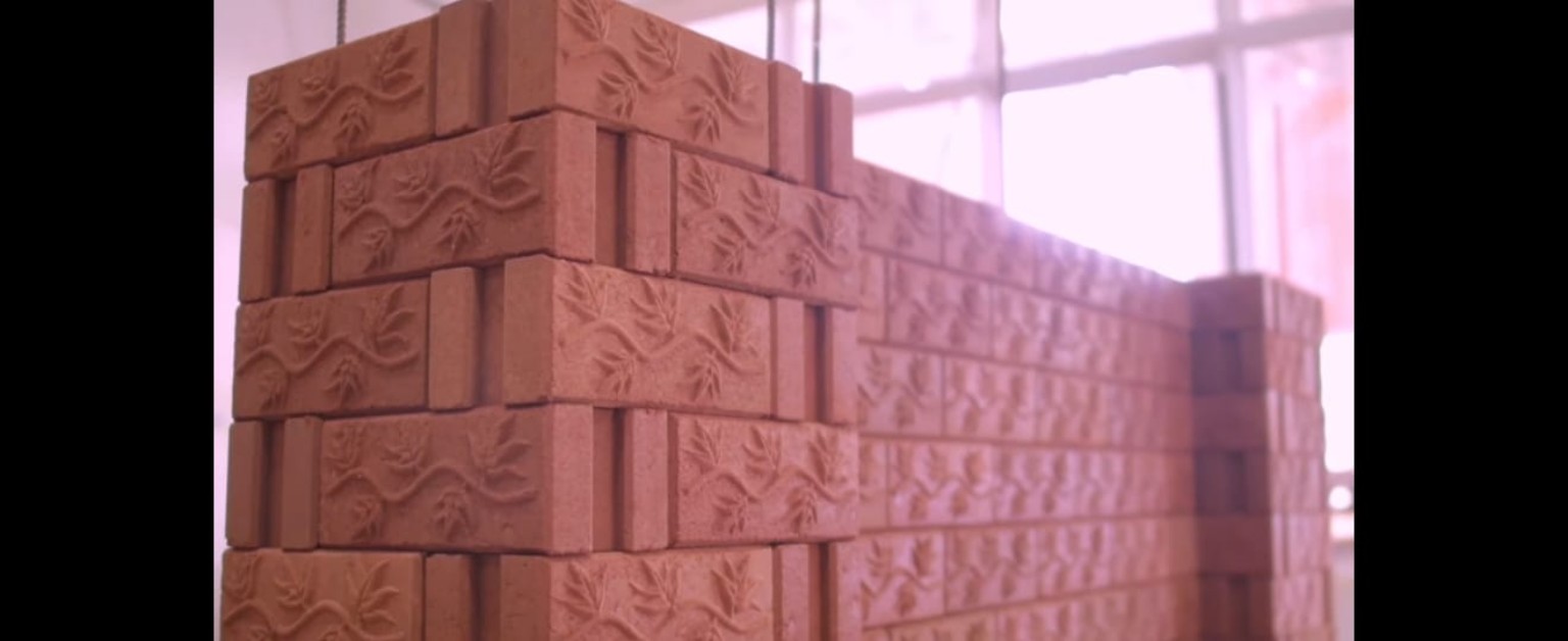 Mur d’exposition composé de blocs de terre décorés de motifs végétaux